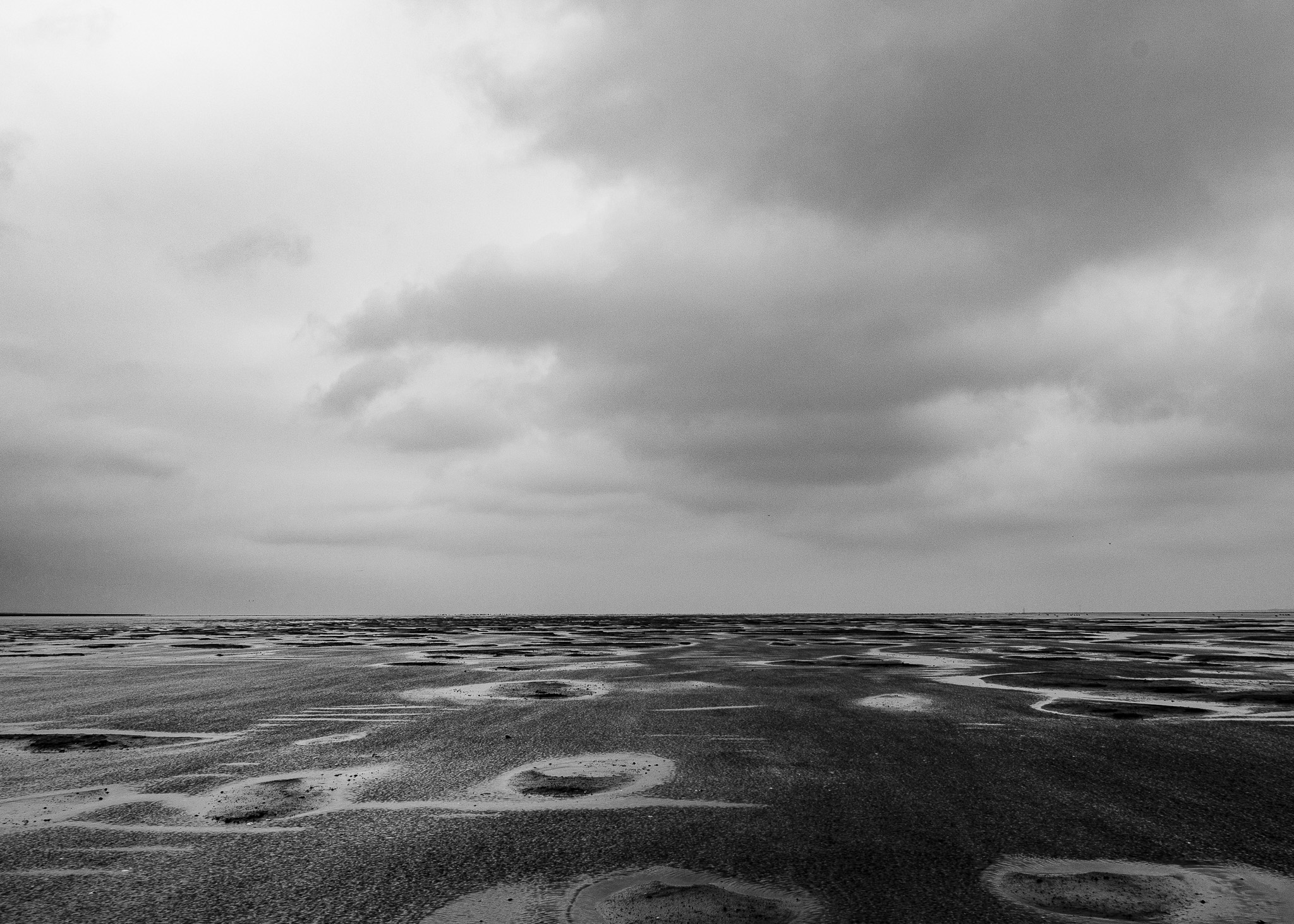 schwarzweiße Weitwinkelaufnahme des Wattenmeers.